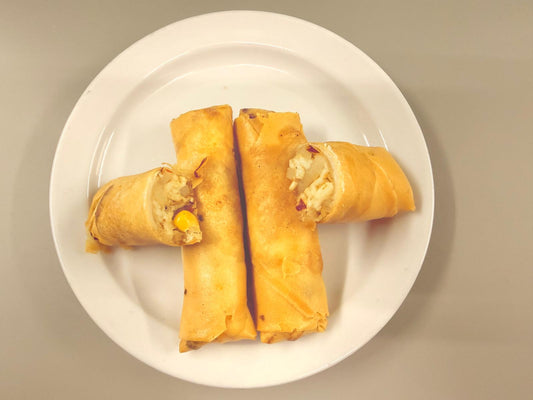 Three golden-brown spring rolls with visible rice and vegetable fillings, arranged on a white plate against a neutral gray background.